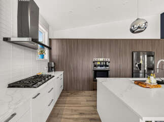 Experience modern luxury in this stunning kitchen, featuring sleek white cabinetry and a marble-patterned countertop.