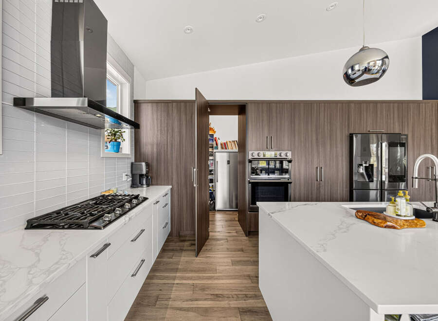 Experience modern luxury in this stunning kitchen, featuring sleek white cabinetry and a marble-patterned countertop.