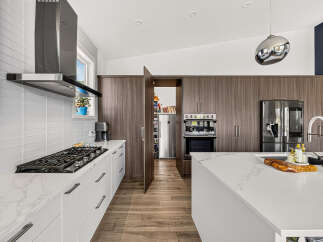 Experience modern luxury in this stunning kitchen, featuring sleek white cabinetry and a marble-patterned countertop.