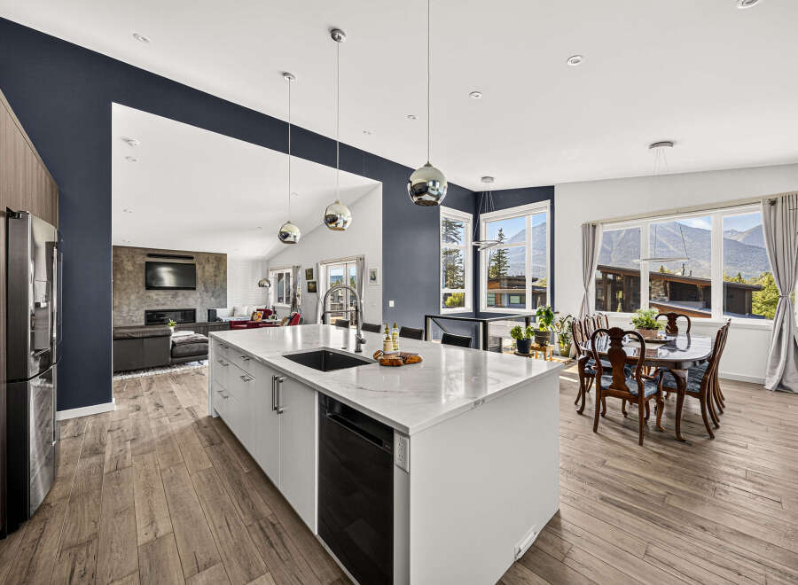 Experience modern living in this stunning open-concept kitchen and living area, featuring a large island with a waterfall countertop and sleek cabinetry.