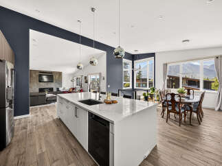 Experience modern living in this stunning open-concept kitchen and living area, featuring a large island with a waterfall countertop and sleek cabinetry.