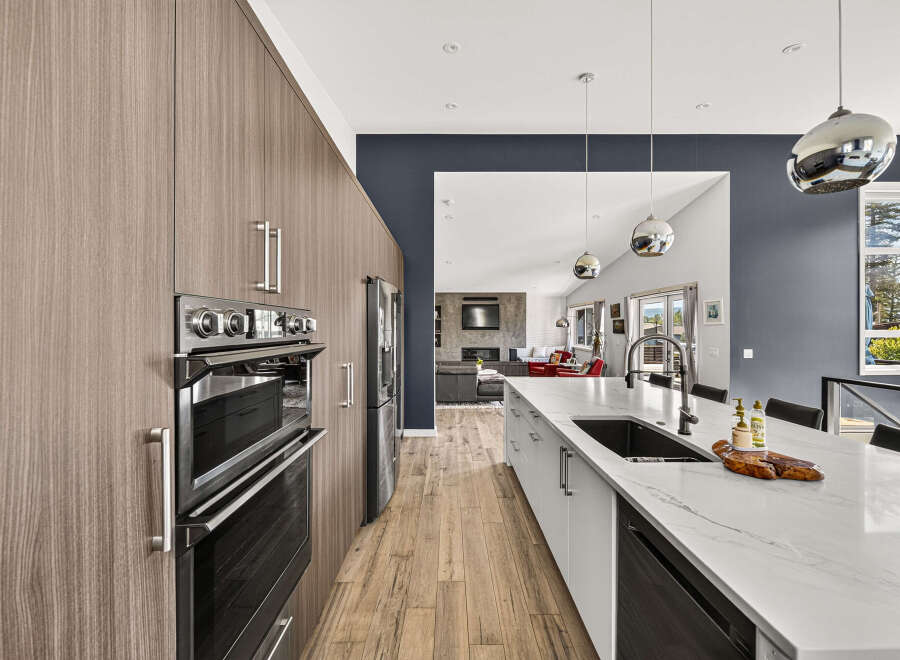 Experience modern luxury in this stunning kitchen, featuring sleek, wood-grain cabinetry and a spacious island with a waterfall countertop.