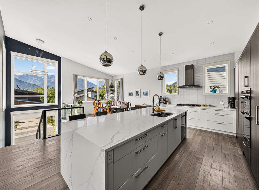 Experience modern living in this stunning kitchen featuring a large quartz island with ample seating and a sleek undermount sink.