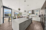 Experience modern living in this stunning kitchen featuring a large quartz island with ample seating and a sleek undermount sink.