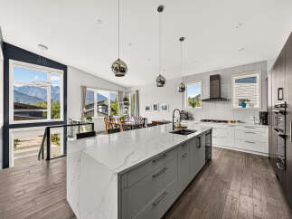 Experience modern living in this stunning kitchen featuring a large quartz island with ample seating and a sleek undermount sink.