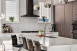 Experience modern luxury in this stunning kitchen, featuring sleek white cabinetry, a sophisticated dark range hood, and a beautiful marble island perfect for entertaining.