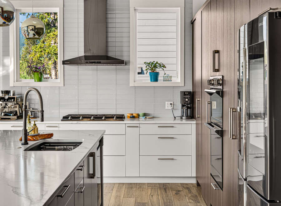 Experience modern luxury in this stunning kitchen, featuring sleek white cabinetry, a sophisticated gas range, and a high-end espresso machine.