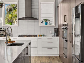 Experience modern luxury in this stunning kitchen, featuring sleek white cabinetry, a sophisticated gas range, and a high-end espresso machine.