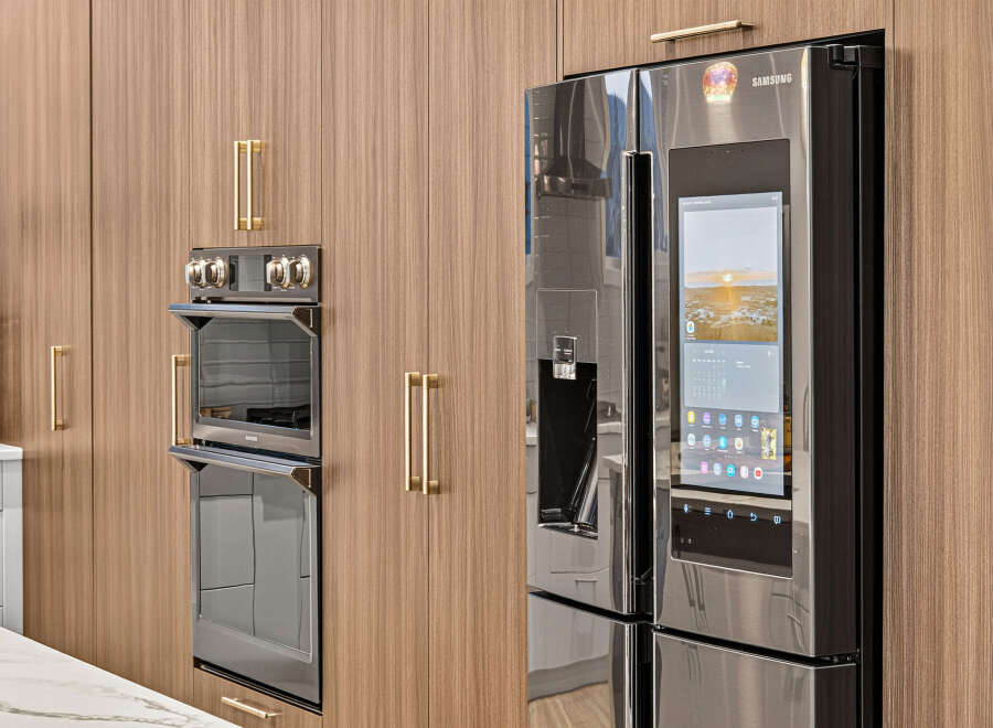 Experience modern luxury in this kitchen, featuring sleek, integrated appliances and warm wood cabinetry.