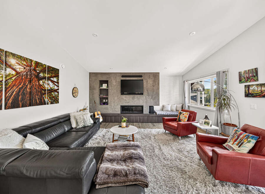 Experience modern living in this spacious living room, featuring a sleek black leather sectional sofa and two vibrant red accent chairs.
