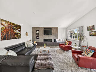Experience modern living in this spacious living room, featuring a sleek black leather sectional sofa and two vibrant red accent chairs.