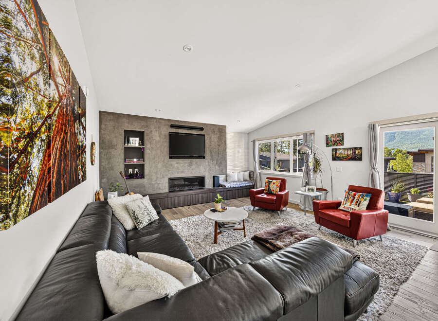 Experience modern living in this spacious living room, featuring a sleek entertainment center with a fireplace and a large sectional sofa perfect for gatherings.