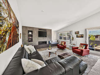 Experience modern living in this spacious living room, featuring a sleek entertainment center with a fireplace and a large sectional sofa perfect for gatherings.