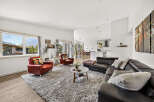 Experience modern living in this spacious open-concept home, featuring a sleek black leather sectional sofa and comfortable red accent chairs.