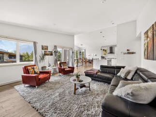 Experience modern living in this spacious open-concept home, featuring a sleek black leather sectional sofa and comfortable red accent chairs.