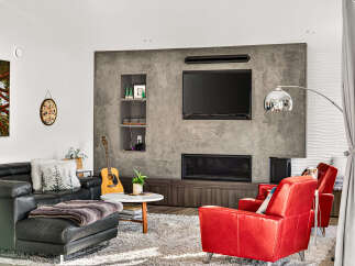 Experience modern living in this stylish living room, featuring a sleek concrete accent wall with a built-in fireplace and entertainment center.