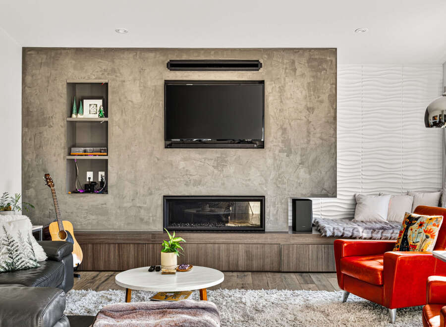 Experience modern living in this stylish living room featuring a sleek concrete accent wall with built-in shelving and a contemporary fireplace.