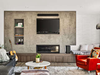 Experience modern living in this stylish living room featuring a sleek concrete accent wall with built-in shelving and a contemporary fireplace.