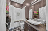 This modern bathroom features a sleek vessel sink atop a dark wood vanity, complemented by a striking floral art piece.