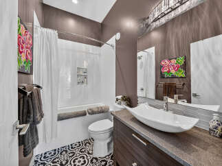 This modern bathroom features a sleek vessel sink atop a dark wood vanity, complemented by a striking floral art piece.