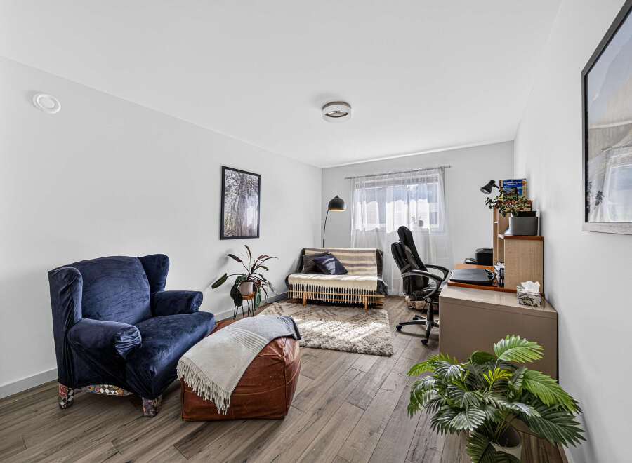 This living room features a comfortable navy blue armchair and a stylish leather ottoman, perfect for relaxing.