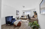This living room features a comfortable navy blue armchair and a stylish leather ottoman, perfect for relaxing.