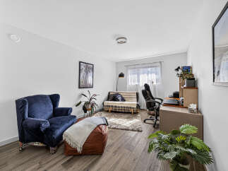 This living room features a comfortable navy blue armchair and a stylish leather ottoman, perfect for relaxing.