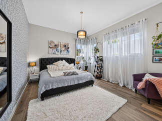 Experience comfort and style in this beautifully appointed bedroom, featuring a plush king-sized bed adorned with soft linens and decorative pillows.