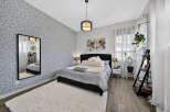 This bedroom features a stylish grey leaf-patterned accent wall, complemented by a plush white rug and a dark upholstered bed.