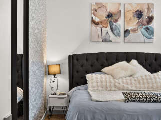 Experience modern comfort in this beautifully appointed bedroom, featuring a plush, tufted headboard and luxurious bedding.