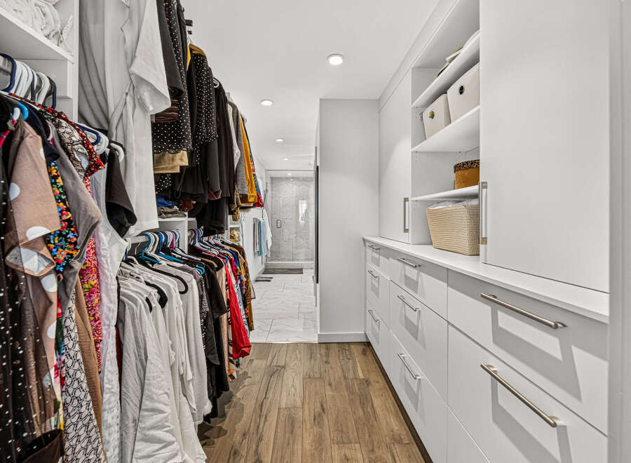 Step into this spacious walk-in closet, featuring ample hanging space for your wardrobe and built-in shelving for organized storage.
