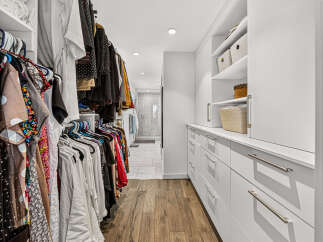 Step into this spacious walk-in closet, featuring ample hanging space for your wardrobe and built-in shelving for organized storage.