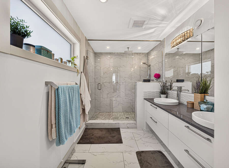 Experience modern luxury in this stunning bathroom, featuring a spacious walk-in shower with elegant marble tile and a rainfall showerhead.