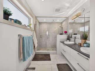 Experience modern luxury in this stunning bathroom, featuring a spacious walk-in shower with elegant marble tile and a rainfall showerhead.