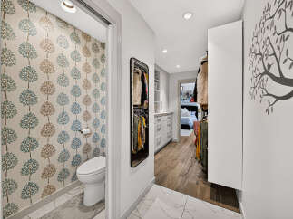 Step into a stylish and functional space featuring a chic powder room with whimsical tree-patterned wallpaper.