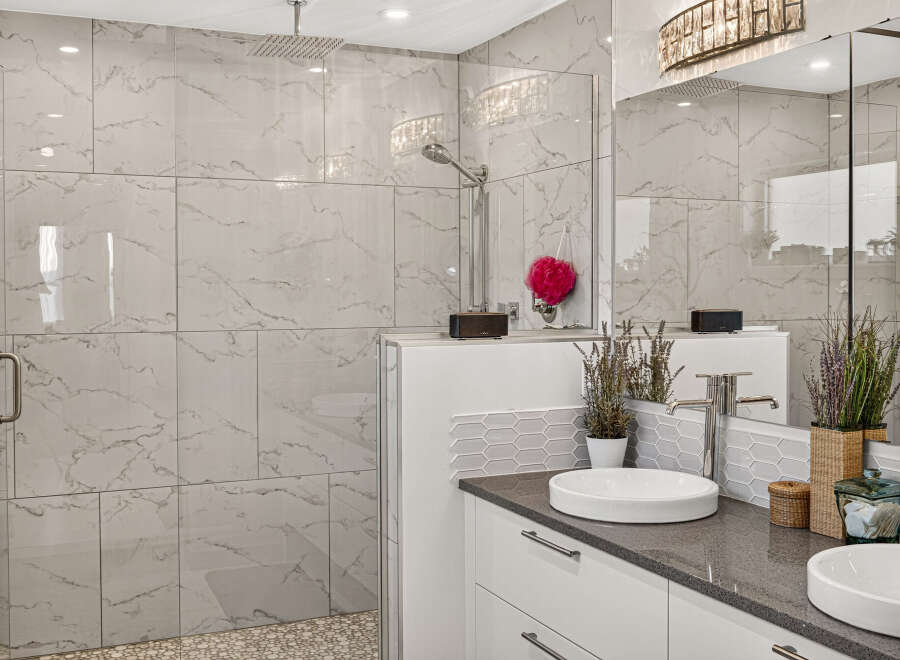 Experience luxury in this modern bathroom featuring a spacious walk-in shower with elegant marble-look tiles and a rainfall showerhead.