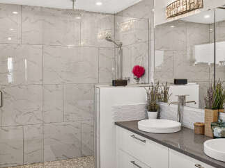 Experience luxury in this modern bathroom featuring a spacious walk-in shower with elegant marble-look tiles and a rainfall showerhead.