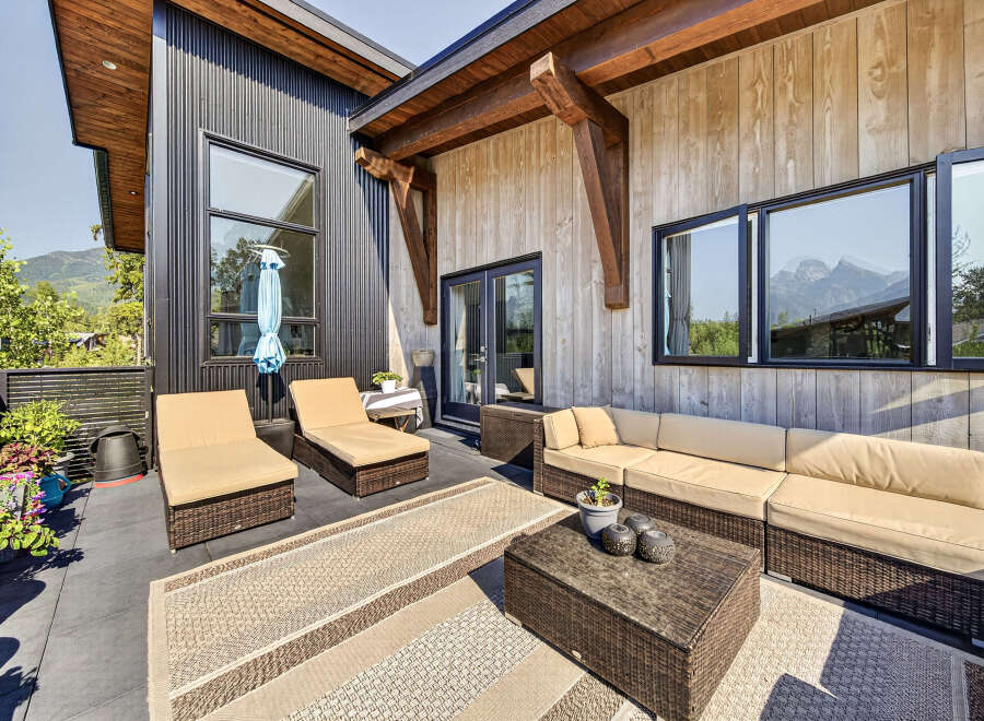 Experience outdoor living at its finest on this spacious patio, featuring comfortable lounge chairs and a sectional sofa perfect for entertaining.
