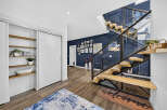 Step into a modern entryway featuring a striking floating staircase with glass railings and warm wood treads.