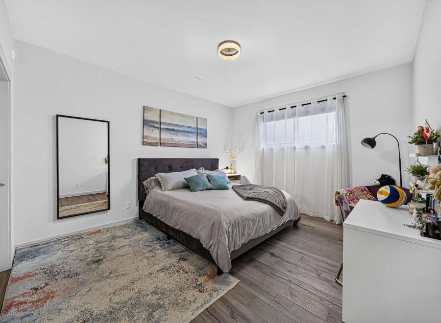 This inviting bedroom features a plush upholstered headboard and a comfortable bed adorned with decorative pillows and a cozy throw.