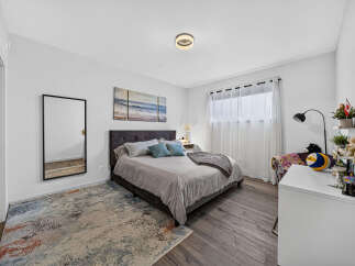 This inviting bedroom features a plush upholstered headboard and a comfortable bed adorned with decorative pillows and a cozy throw.