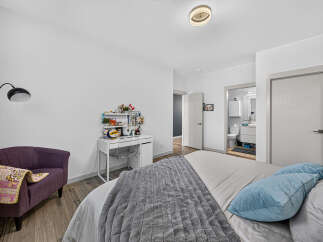 Discover this charming bedroom featuring a comfortable bed with plush blue pillows and a cozy grey throw blanket.