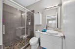 Experience modern luxury in this stunning bathroom, featuring a sleek glass-enclosed shower with elegant grey tile and a unique pebble floor.