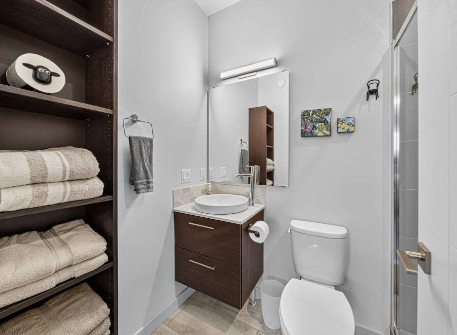 Discover this modern bathroom featuring a sleek vanity with a vessel sink and ample storage.