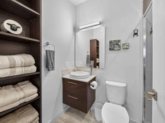 Discover this modern bathroom featuring a sleek vanity with a vessel sink and ample storage.