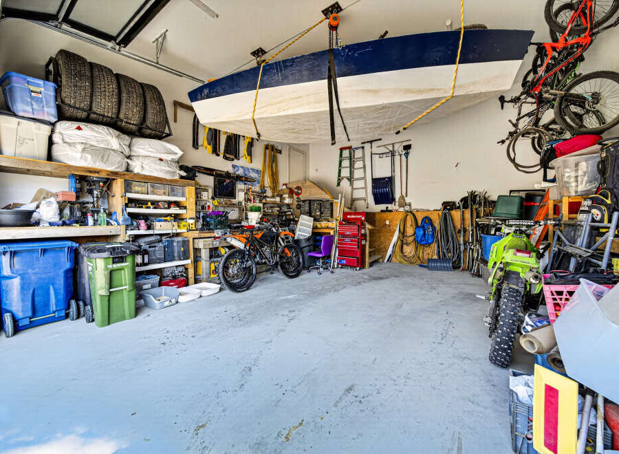 This spacious garage offers ample storage solutions, including overhead boat storage and wall-mounted shelving for tires and supplies.
