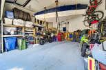 This spacious garage offers ample storage solutions, including overhead boat storage and wall-mounted shelving for tires and supplies.