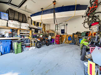 This spacious garage offers ample storage solutions, including overhead boat storage and wall-mounted shelving for tires and supplies.