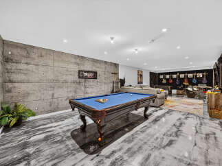 Experience ultimate entertainment in this modern basement featuring a professional pool table and a dedicated music area with guitars and a drum set.