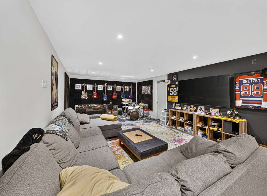 This entertainment room is a music lover's paradise, featuring a collection of guitars displayed on the wall and a full drum set ready for action.